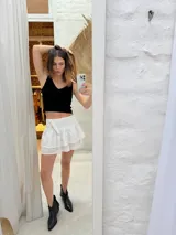 Minifalda negra con bordado inglés, cintura alta y detalle de argollas metálicas en el lateral.