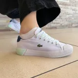 Championes Lacoste Gripshot de lona blanca con detalles en azul marino en el talón y verde agua en los cordones y la suela.