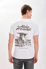 Remera blanca de manga corta con cuello redondo y estampado trasero en tono sepia/marrón. El estampado incluye el texto "Aloha Hawaii" y una ilustración de una caseta de salvavidas con el texto "Paradise of the Pacific".
