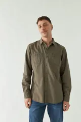 Camisa de gabardina gris con corte slim, mangas largas, cartera abotonada y dos bolsillos con solapa en el pecho.