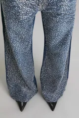 Pantalón de jean de tiro medio y corte wide leg, color azul, con apliques de strass plateados.