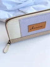 Billetera de cuero color lila, con cierre metálico y monedero interno, ideal para billetes extendidos.