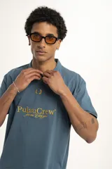 Remera azul con cuello polo y estampado amarillo con el texto "Pulau Crew for me for you".