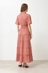 Maxi vestido rojo con estampado de rombos, corte camisero, cuello clásico, mangas cortas abullonadas con puños elásticos, cintura elastizada y falda larga escalonada.