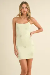Vestido corto ajustado al cuerpo color amarillo pálido, con tirantes finos y estampado de estrellas plateadas.