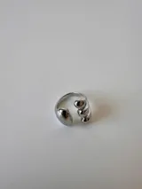 Anillo plateado de acero quirúrgico hipoalergénico con diseño abierto y tres gotas en un extremo y una gota en el otro.