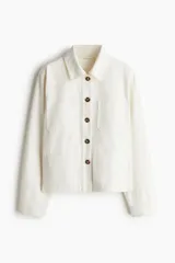 Campera color crudo en sarga de algodón con cuello, botones adelante y canesú en la espalda. Modelo de hombros apenas caídos con bolsillos superiores de parche, bolsillos insertados adelante y puños abotonados.
