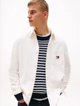 Camisa blanca de algodón con textura moteada, corte oversize, cuello inglés, bolsillo de parche en el pecho y parche de Tommy Jeans en el bolsillo.