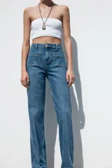 Pantalón de jean de tiro alto con bolsillos frontales y traseros. Corte recto y cierre frontal con cremallera y botón.