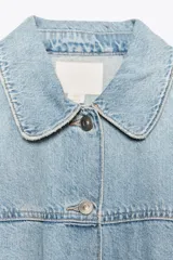 Cazadora de denim celeste con cuello solapa y manga tres cuartos. Cierre frontal con botones metálicos.