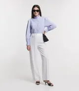 Pantalón blanco de crepé, corte recto, con trabillas en la cintura, cierre con botón y cremallera, y colgante de corazón metálico.