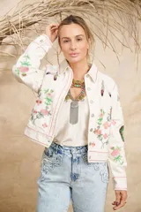 Campera de algodón color blanco con estampado de flores, plumas y colibríes, cuello camisero y cierre frontal con botones.