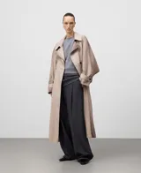 Gabardina cruzada color topo (gris claro/beige) con efecto envejecido, corte recto y doble botonadura. Presenta solapa doble en el lado derecho, manga larga con trabilla en el puño, y cinturón del mismo tejido.