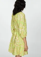 Vestido de corte corto con estampado floral en tonos verdes y amarillos, con mangas abullonadas y escote en V.