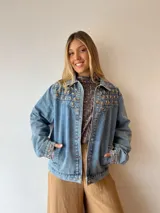 Campera de jean celeste con tachas doradas en forma de estrella en la parte superior de la espalda y los puños.