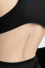 Vestido corto negro ajustado al cuerpo, con cuello redondo y sin mangas.