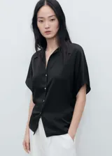 Camisa negra de manga corta con tejido satinado, cuello camisero y cierre frontal con botones.