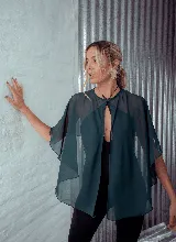 Capa corta color verde esmeralda de gasa transparente, con cuello redondo y abertura frontal con cierre de botón.