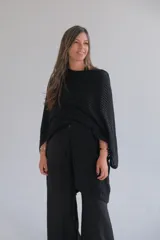 Ruana negra de punto con cuello redondo y diseño asimétrico.