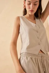 Chaleco color beige con botones decorativos con forma de ananá.