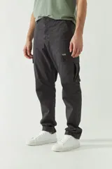 Pantalón cargo color beige para hombre, de corte recto, con bolsillos laterales y traseros. Se ajusta a la cintura con cinturón de cuero marrón.