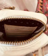 Bandolera pequeña color crudo con diseño acolchado en forma de rombos. Incluye correa larga regulable y tarjetero interno.