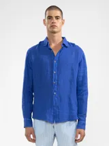 Camisa celeste de lino, de manga larga con botones de coco y parche de la marca.