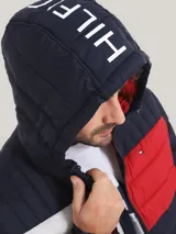 Campera acolchada Tommy Hilfiger, con capucha y cierre frontal. Diseño color block en azul marino, blanco y rojo.