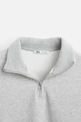 Sudadera negra de cuello alto con cierre frontal de cremallera, corte relaxed fit, manga larga y terminaciones en rib.