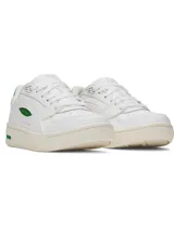 Zapatillas deportivas de mujer Under Armour modelo UA W Flex, color blanco con detalles en verde esmeralda. Presentan una silueta de corte bajo inspirada en el estilo retro de baloncesto, con parte superior de cuero y suela de goma color crema. El logo de Under Armour es visible en el lateral y en el talón.