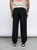 Pantalón deportivo negro de nylon con detalles en contraste blanco y logo de Umbro bordado en el lateral. Corte relajado.