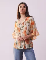 Blusa de gasa estampada con flores color naranja, marca Figueroa & Flower. Tiene cuello a la base, escote en V con lazo, abertura central con botones, delantera plisada y mangas 3/4 amplias.