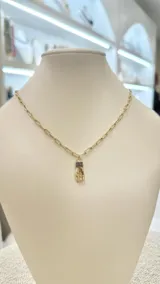 Collar dorado con cadena de eslabones rectangulares y dije de mano con detalles de circonitas negras.