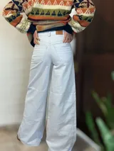 Pantalón de jean blanco tiza, de corte ancho y tiro alto, con bolsillos delanteros y traseros.