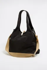 Bolso de mano grande de nailon negro con estructura blanda. Tiene doble asa de mano, asa de tejido regulable, etiqueta logotipada BIMBA Y LOLA, acabados metálicos, bolsillo interior y cierre de cordón.