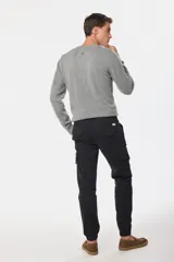 Pantalón cargo de color verde militar, con múltiples bolsillos y ajuste en los tobillos.