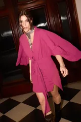 Vestido corto fucsia tipo kimono con mangas abiertas y tiras ajustables en la cintura.