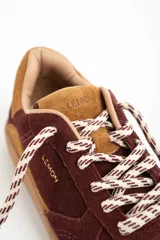 Zapatilla de cuero con capellada de gamuza en tonos borgoña y camel, con suela de goma color caramelo. Cordones trenzados en blanco y marrón.