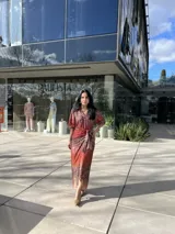Vestido camisero midi con estampado animal print en tonos marrones y rojizos. Tiene cuello camisero, mangas largas con puños abotonados y lazo para ajustar en la cintura.
