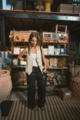 Pantalón de vestir negro de tiro alto, corte recto y pierna ancha. Presenta pliegues frontales y bolsillos laterales.