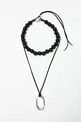 Collar doble con cadena de cuentas negras y dije transparente en forma de gota.