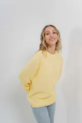 Sweater de punto color amarillo claro, de corte amplio, con escote redondo y puños ajustados.
