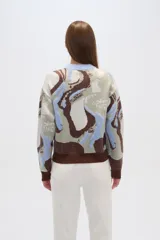 Sweater de punto con estampado abstracto en tonos marrón, celeste, blanco y verde. Tiene cuello redondo y corte holgado.