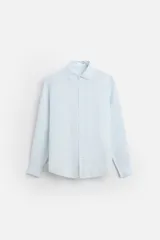 Camisa celeste de lino, de corte recto, manga larga y cuello clásico.