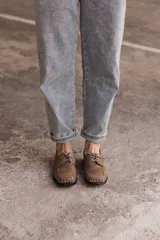 Mocasín de cuero negro con cordones y tachas metálicas en la puntera.