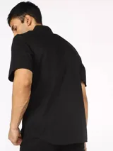Camisa negra de manga corta con corte slim fit, cuello clásico y cierre con botones.