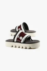 Sandalia con base alta, capellada ancha con acabado brillante y estructura acolchada. Suela dentada.