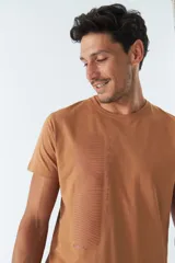 Remera color marrón con cuello redondo y manga corta. Presenta un estampado vertical con texto en japonés y líneas onduladas. Corte recto.