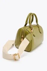 Bolso formato mini bowling color verde oliva con detalles metálicos dorados en las asas. Tiene doble asa de mano y correa bandolera extraíble. Incluye bolsillo interior con cremallera y cierre principal con cremallera.