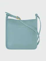 Bandolera Longchamp modelo Le Foulonné, color crudo, con correa fina regulable, cierre superior y logo grabado en el frente.